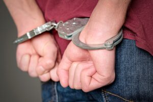 Person in handcuffs surrounded by police officers illustrating a stressful arrest situation.