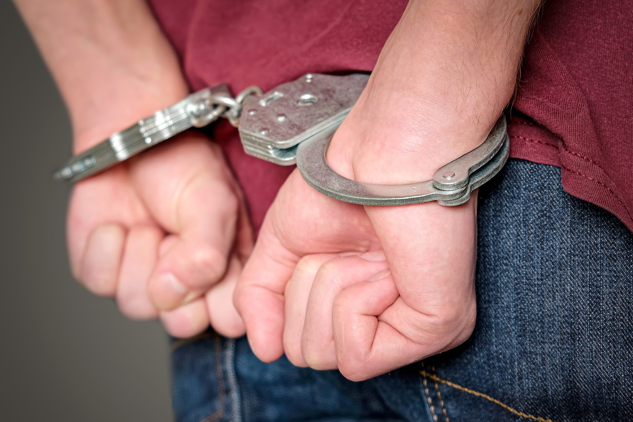 Person in handcuffs surrounded by police officers illustrating a stressful arrest situation.